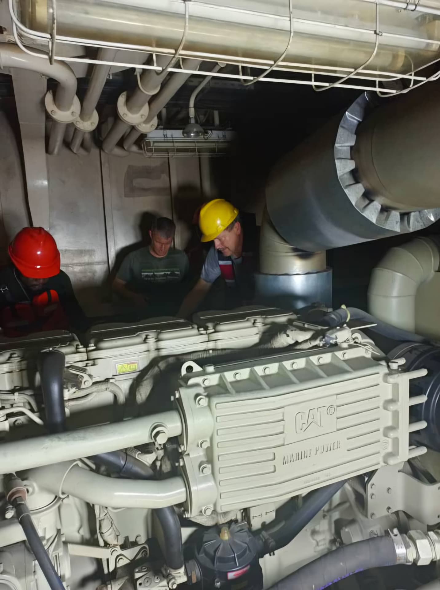 Engineers inspecting the CAT marine main engine in the MV SUYOUHAO engine room