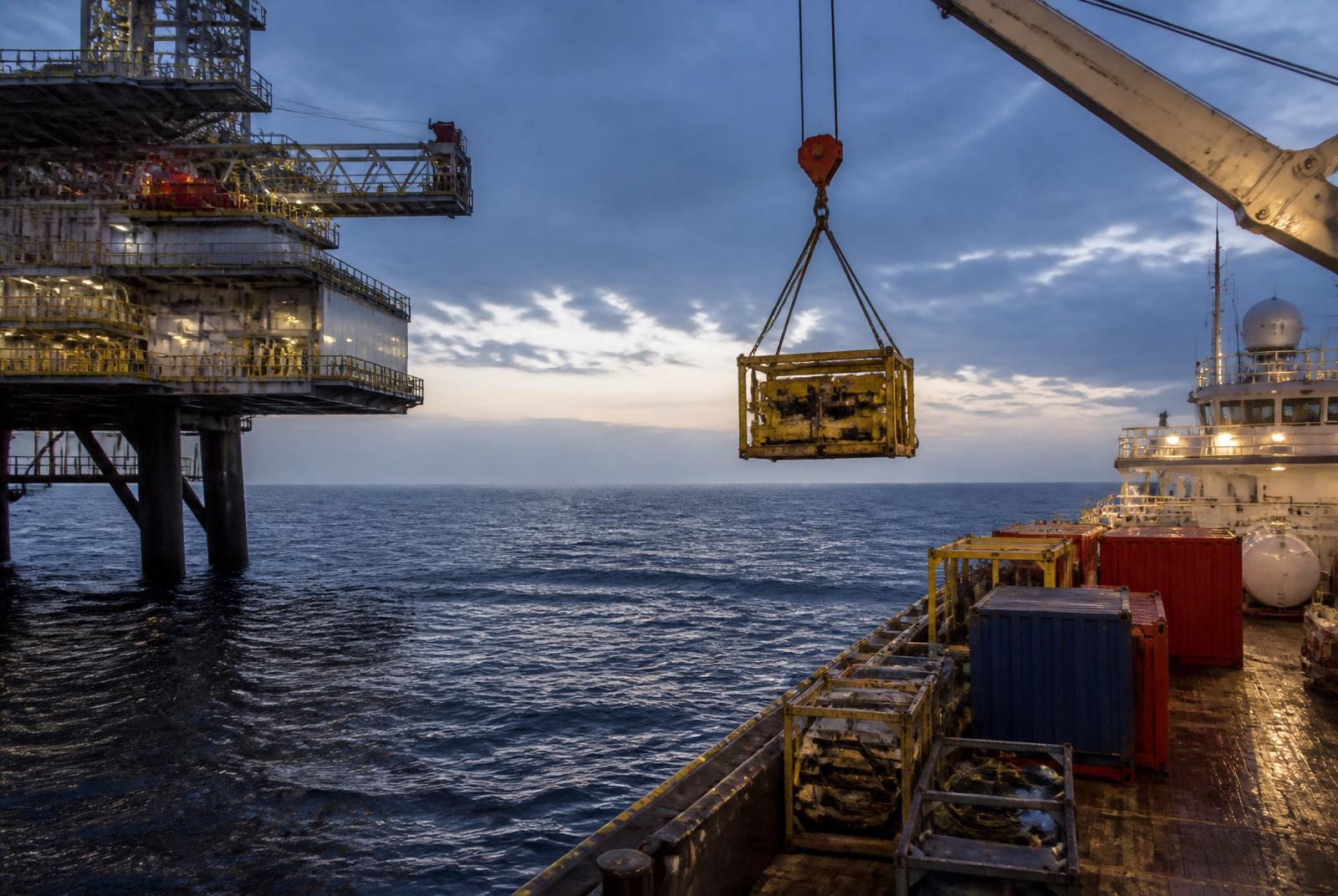 Offshore supply vessel transferring cargo alongside an offshore platform